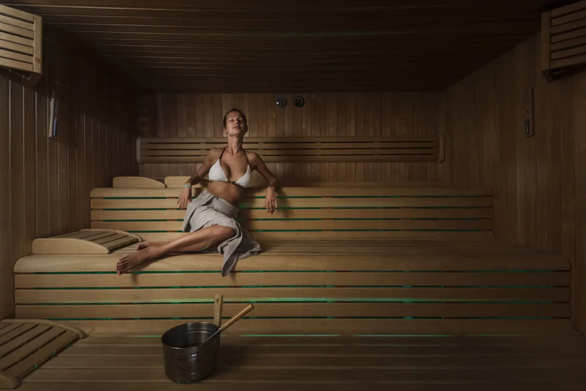 Ragazza in bikini bianco nella sauna finlandese, in relax.